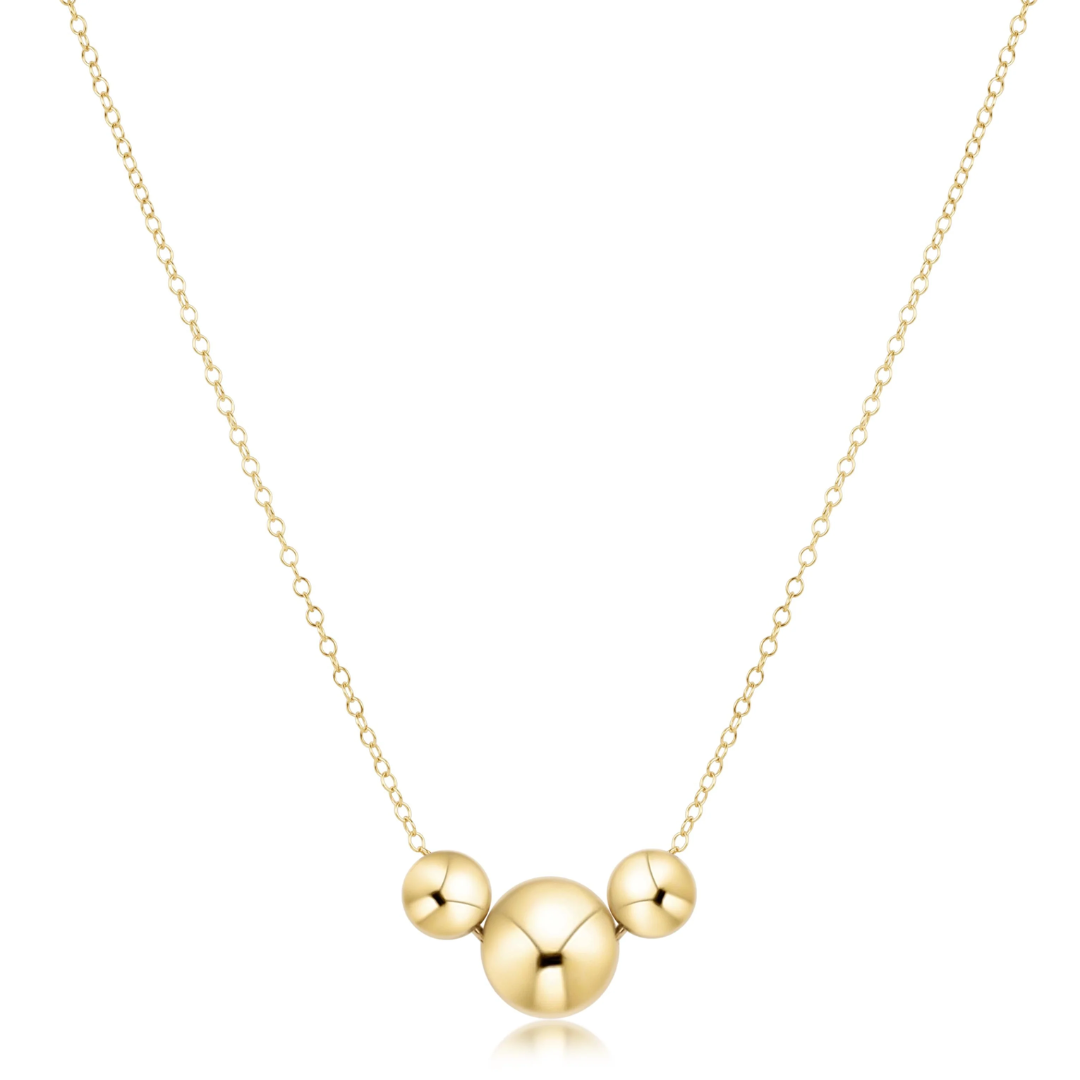 Gold necklace with three round pendants on a white background