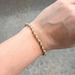 gold and silver beaded bracelet on hand against neutral backgroud
