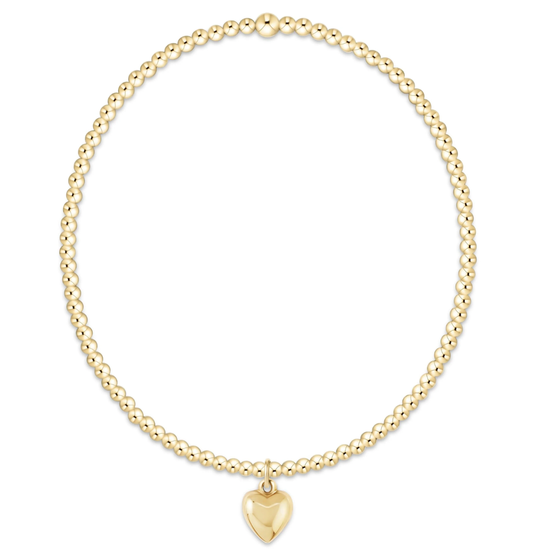 A delicate gold beaded necklace with a small polished heart-shaped pendant, displayed on a clean white background.