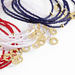 Bracelets with red, white, and blue cord and gold charm on a white background