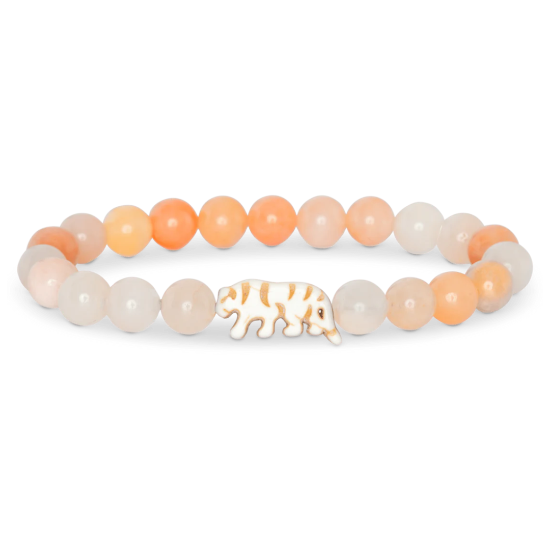 Bracelet with peach and white beads and a tiger charm on a white background