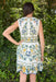 Woman wearing a floral dress standing in front of green foliage