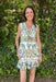 Woman wearing a floral dress standing in front of green foliage