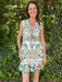 Woman wearing a floral dress standing in front of green foliage