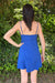 Woman wearing a blue dress standing in front of green foliage