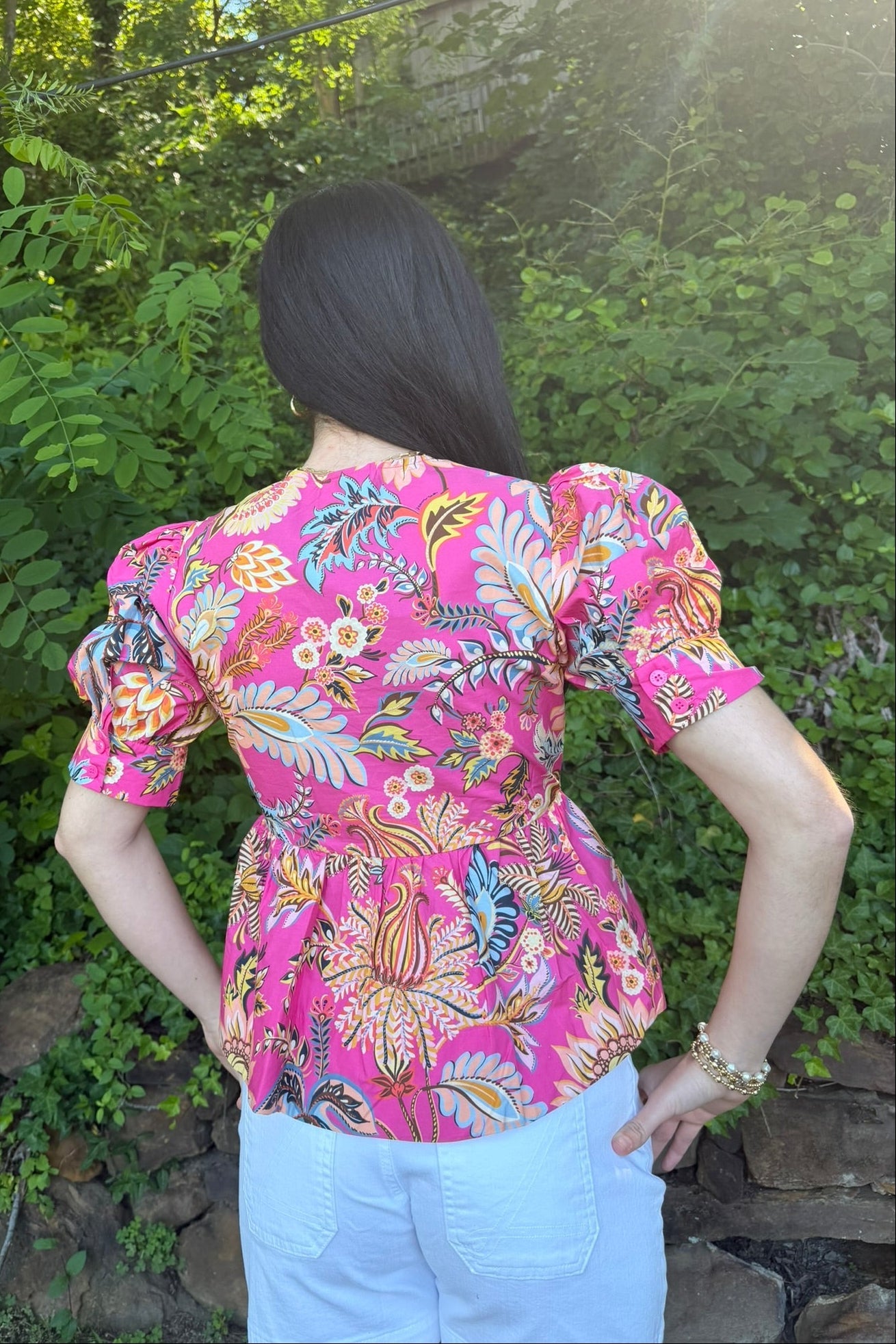 Person wearing a colorful floral blouse with a natural background