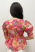 Person wearing a vibrant pink floral blouse against a plain background