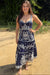 Woman wearing a blue embroidered dress standing on a sandy path with greenery in the background