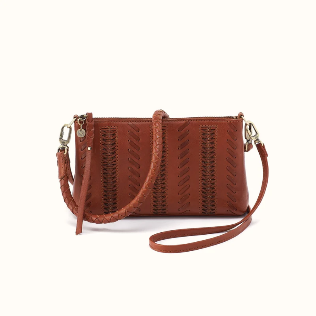 A brown leather crossbody handbag with a braided top handle, a long shoulder strap, and a zip-around closure, shown on a plain off-white background.