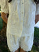 White lace set with gold buttons worn by a person outdoors.