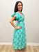 Woman in green dress with patterns against gray background