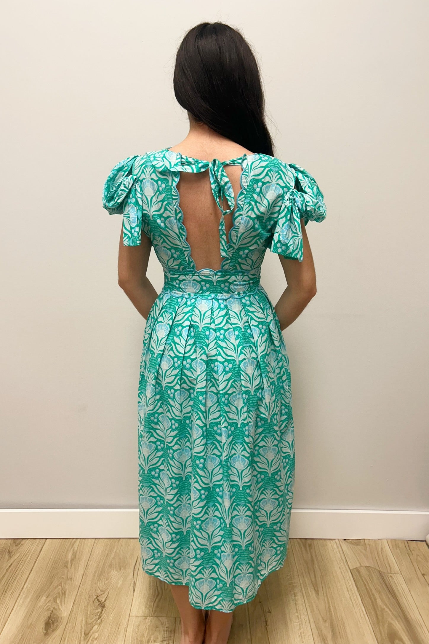 Woman in green dress with patterns against gray background