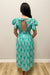 Woman in green dress with patterns against gray background