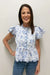 Woman wearing a blue floral blouse and jeans against a plain background