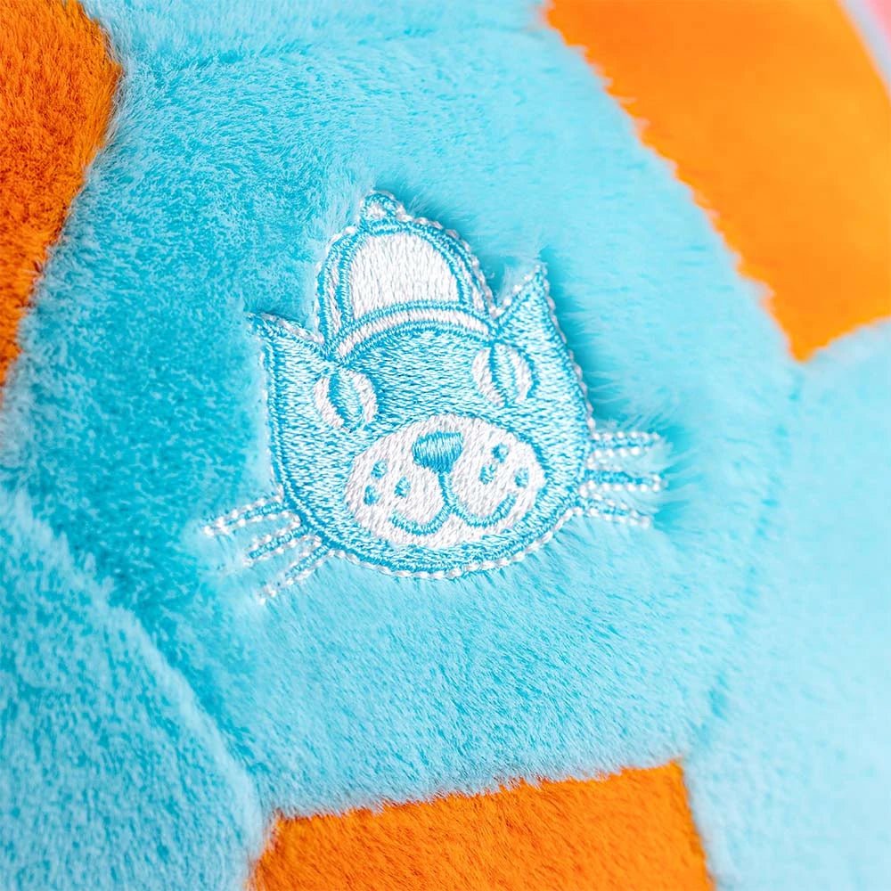 Close-up of the embroidered face on a blue and orange plush soccer ball