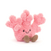 A plush toy resembling coral with a smiling face and pink body, with no background.