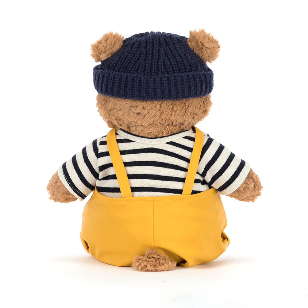 teddy bear with stripe shirt, blue hat and overalls on white background