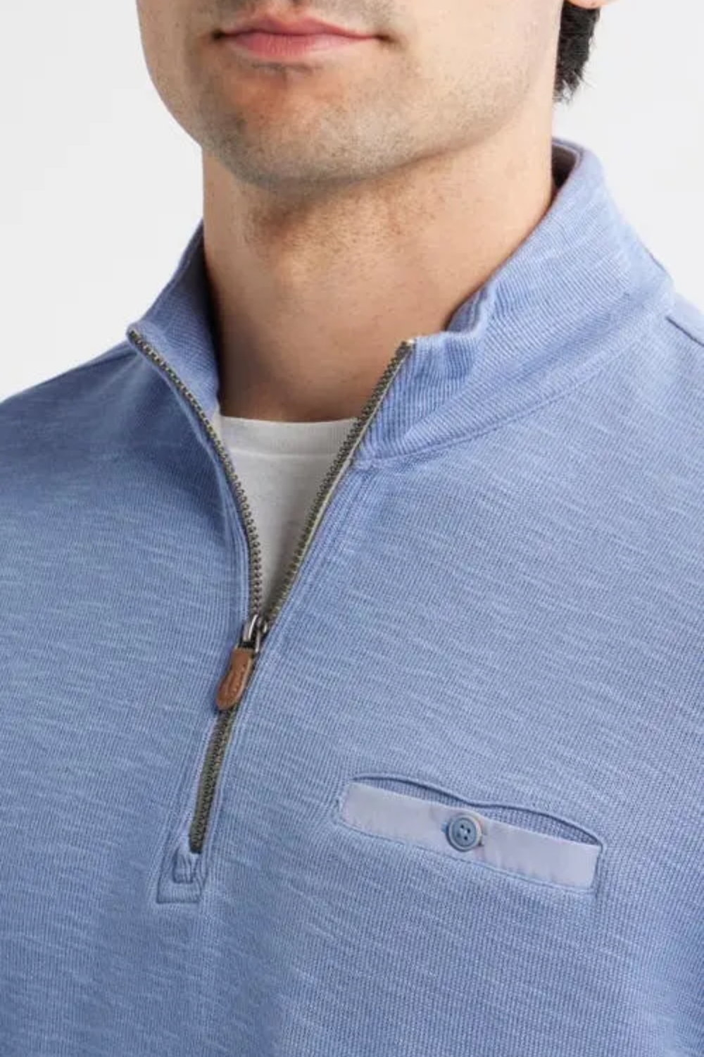 Close-up of a man wearing a light blue quarter-zip pullover with a chest pocket and a white undershirt.