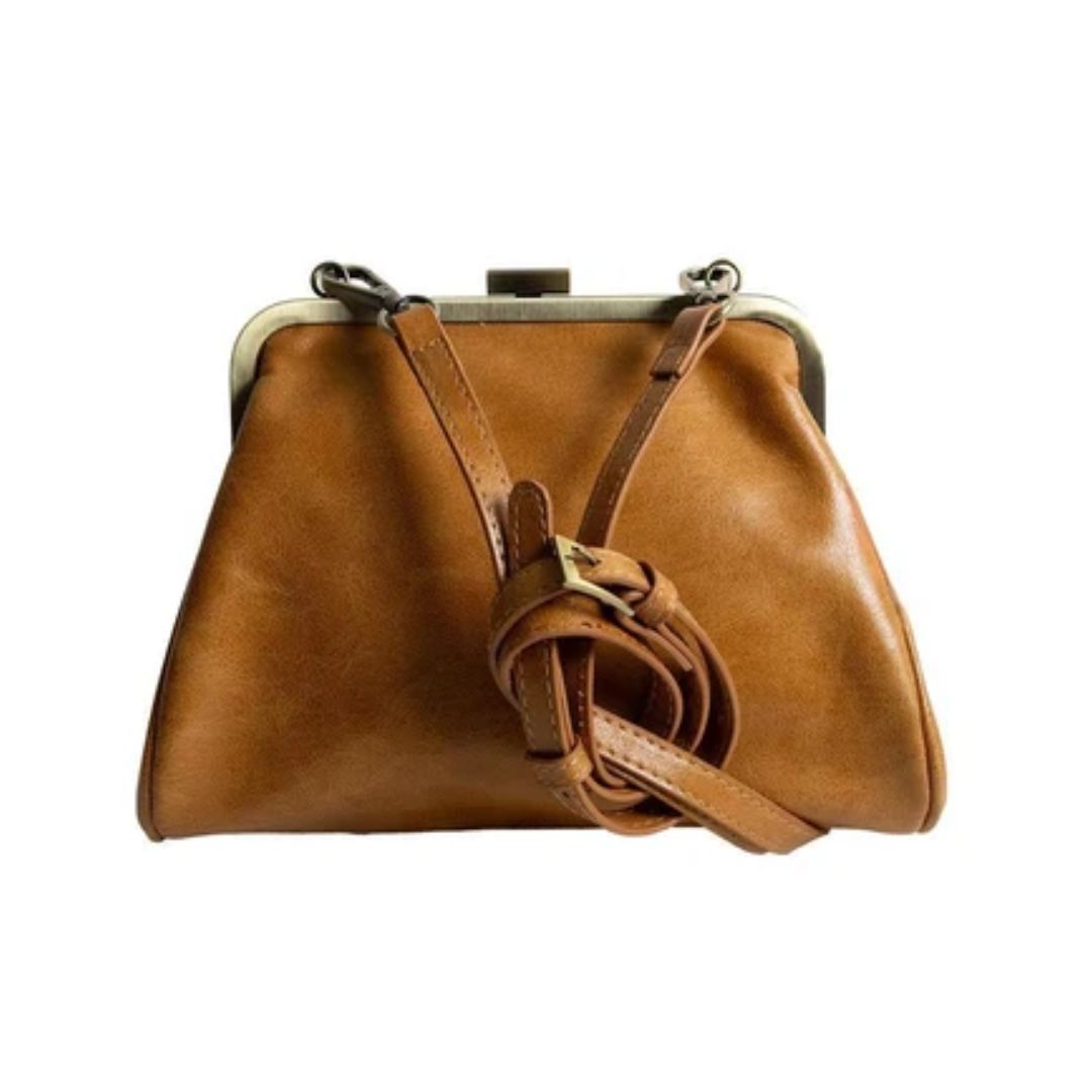 A tan leather kiss-lock handbag with a matching adjustable shoulder strap draped in front, set against a plain white background.