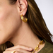 Close-up of a person wearing gold hoop earrings and a matching necklace.
