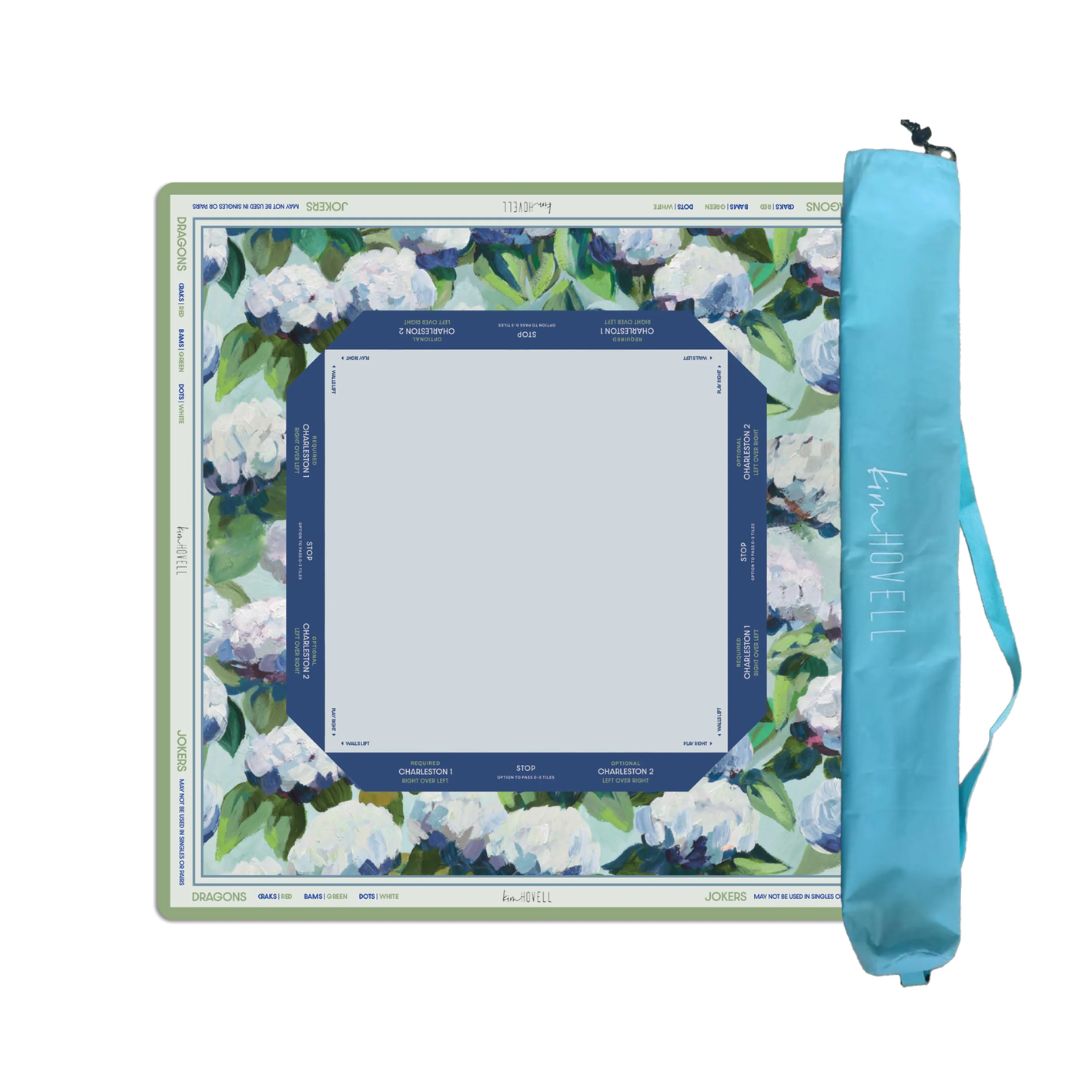A square art canvas with a floral border design in white, green, and blue, shown next to its light blue carrying case on a plain white background.