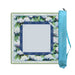 A square art canvas with a floral border design in white, green, and blue, shown next to its light blue carrying case on a plain white background.