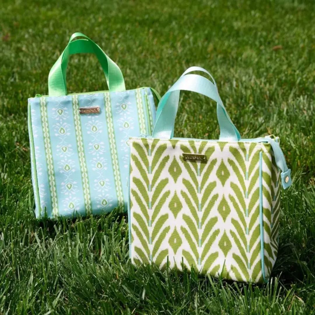 Two patterned bags on grass, one blue and white, one green and white.