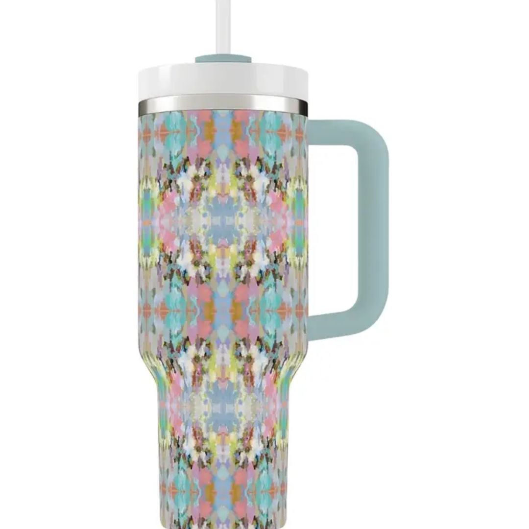 A tall handled tumbler with a pastel multicolor kaleidoscope pattern, featuring a light blue handle and a white lid with a clear straw, shown on a plain white background.