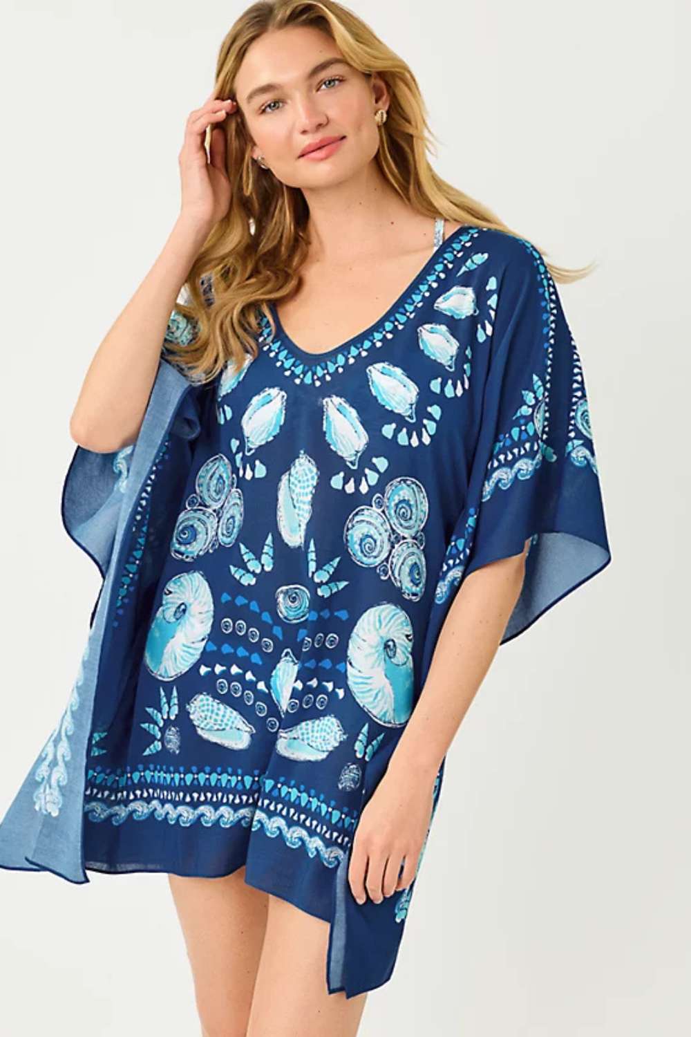Woman wearing a navy blue cover-up with blue floral patterns on a white background
