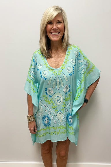 Woman wearing light blue beach cover up with white, blue and green nautical pattern