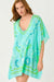 Woman wearing a turquoise and green patterned cover-up on a white background