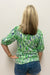 Woman wearing blouse with green and blue pattern with collar