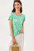 Woman wearing a colorful patterned shirt and holding a straw bag on a white background
