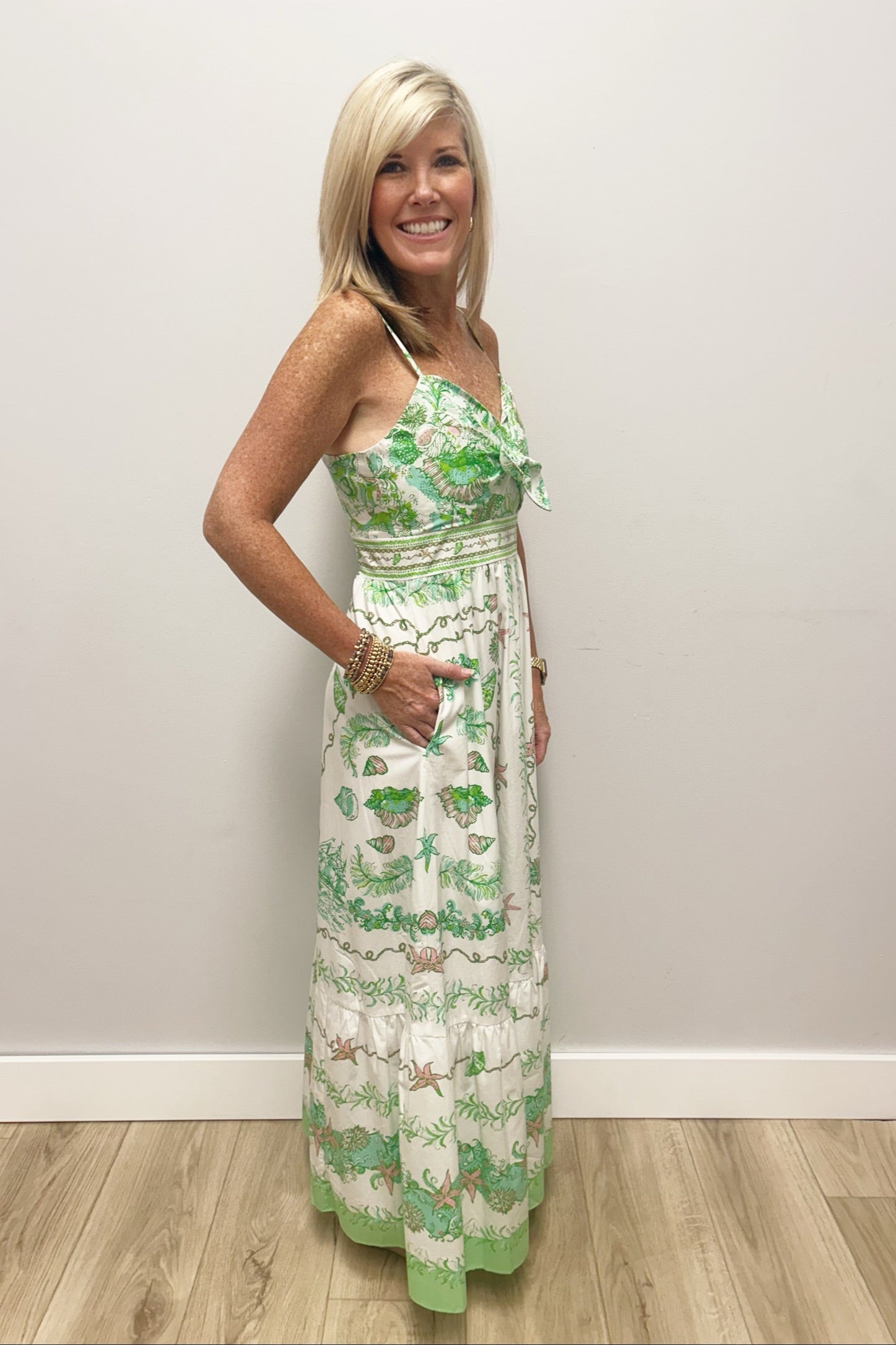 Woman wearing white dress with green and pink patterns and a bow in the front