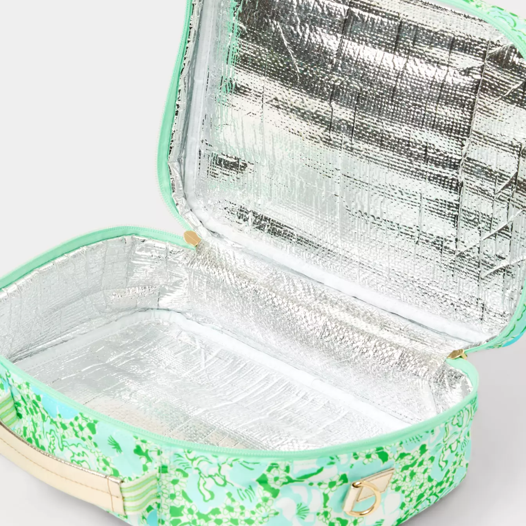 An open insulated lunch bag with a mint green and green floral pattern exterior, a beige handle, and a reflective silver foil lining.