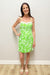 woman wearing bright green floral dress against plain background