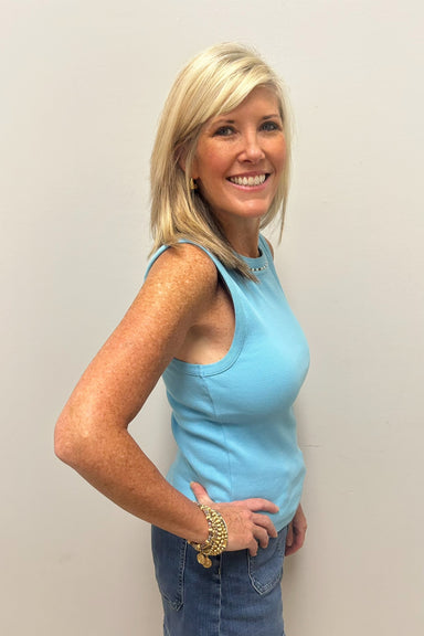 Woman wearing light blue tank top with pearl detail around the neck