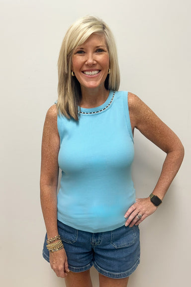 Woman wearing light blue tank top with pearl detail around the neck