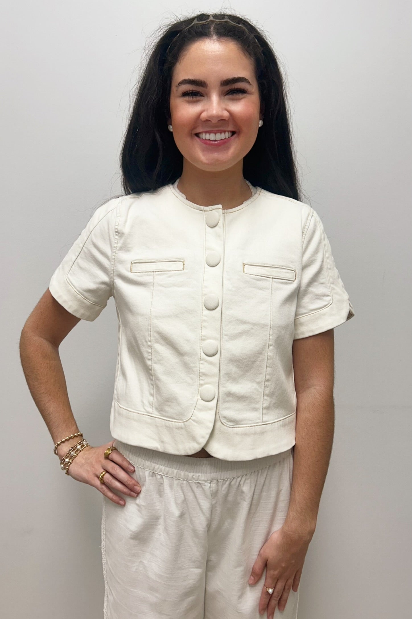 Woman wearing white, short sleeved, button down jacket