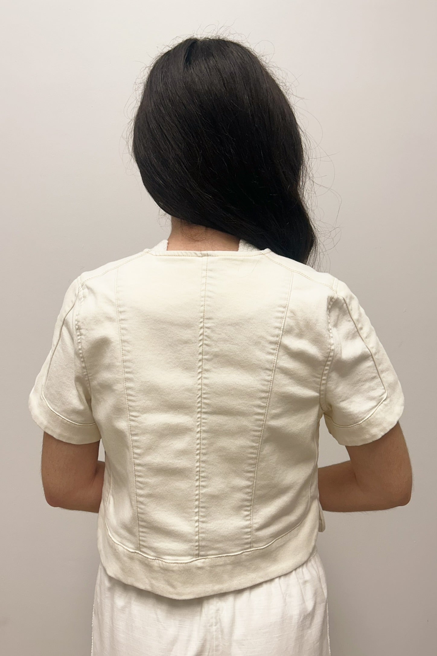 Woman wearing white, short sleeved, button down jacket