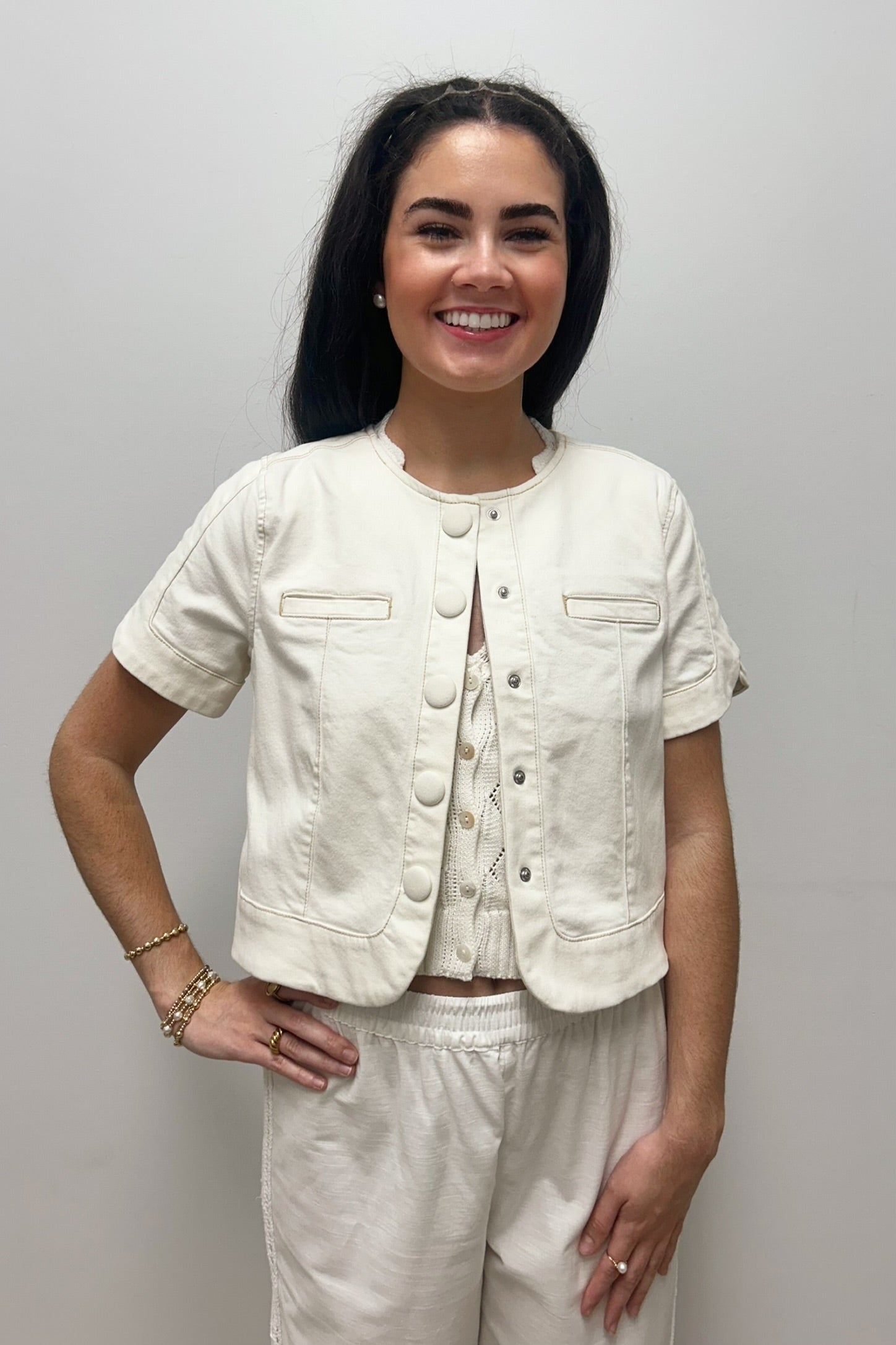 Woman wearing white, short sleeved, button down jacket