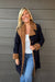 Woman wearing Liverpool Sherpa Notch Collar Jacket In Cinder Bloom with blue jeans on a dark wood background.