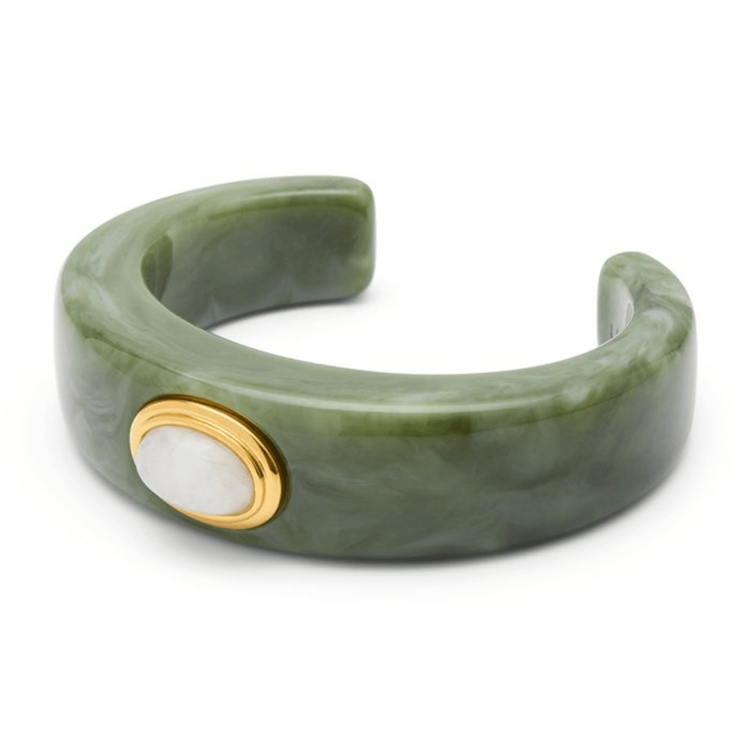 A green marbled resin cuff bracelet with a gold bezel-set oval white stone accent, shown on a clean white background.