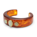 A thick open cuff bracelet made of glossy amber-brown marbled resin, decorated with three oval pale green stones set in gold-tone bezels, shown on a plain white background.