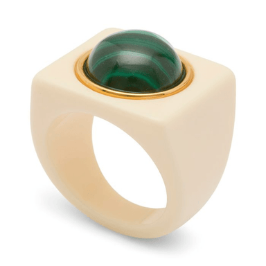A modern statement ring featuring a matte cream-colored square bezel with a large, polished green malachite cabochon and a thin gold bezel setting, shown on a white background.