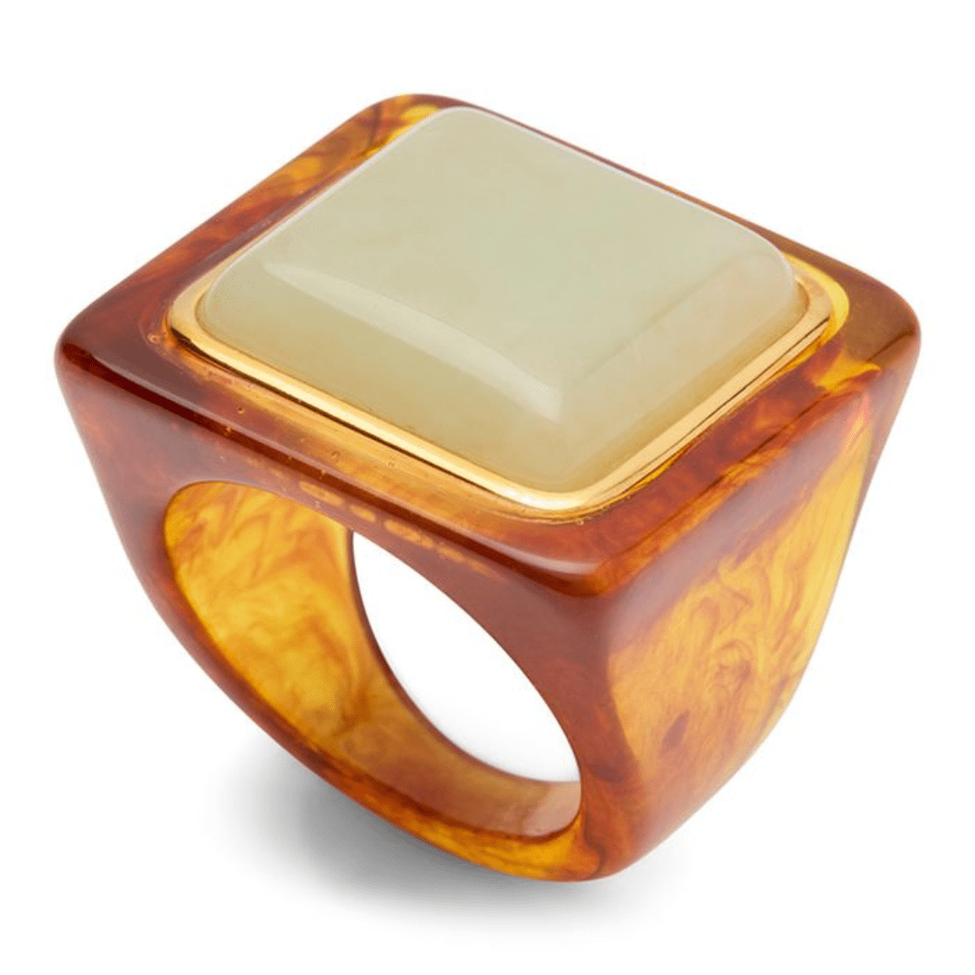 A square-shaped ring with a translucent amber-brown marbled resin band and a light green stone inset in a gold-toned bezel, shown on a white background.