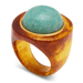 A chunky statement ring featuring a large, smooth, rounded turquoise-blue stone set in a wide, sculptural band made of marbled amber and yellow resin, with a polished gold-toned bezel.