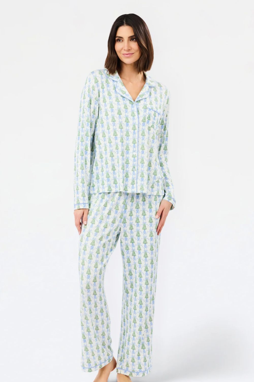 A woman modeling a two-piece pajama set with a light blue and green pineapple print on a white background, photographed against a plain white studio backdrop.