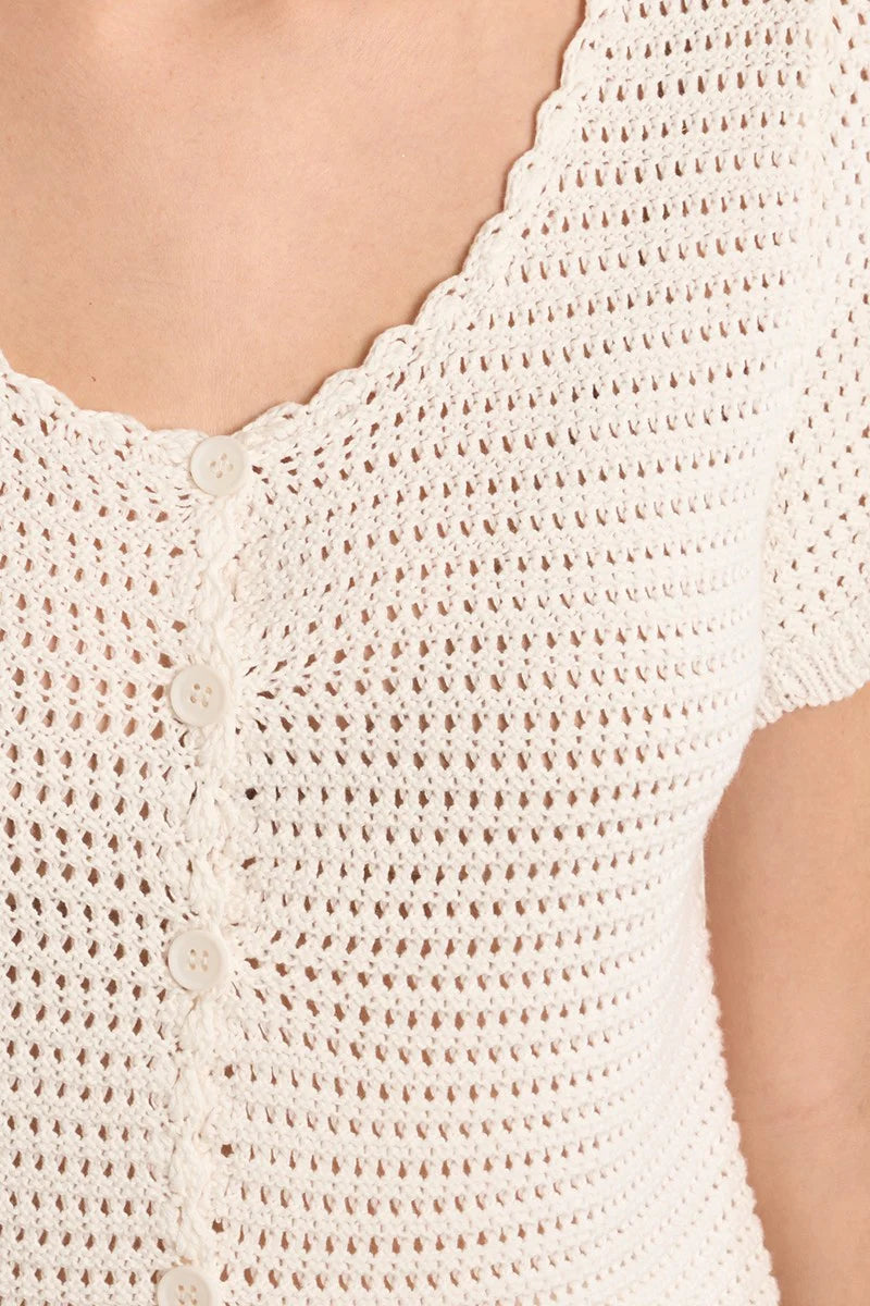 close up of woman in white crochet top with buttons