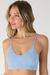 Woman wearing a light blue bralette against a plain background